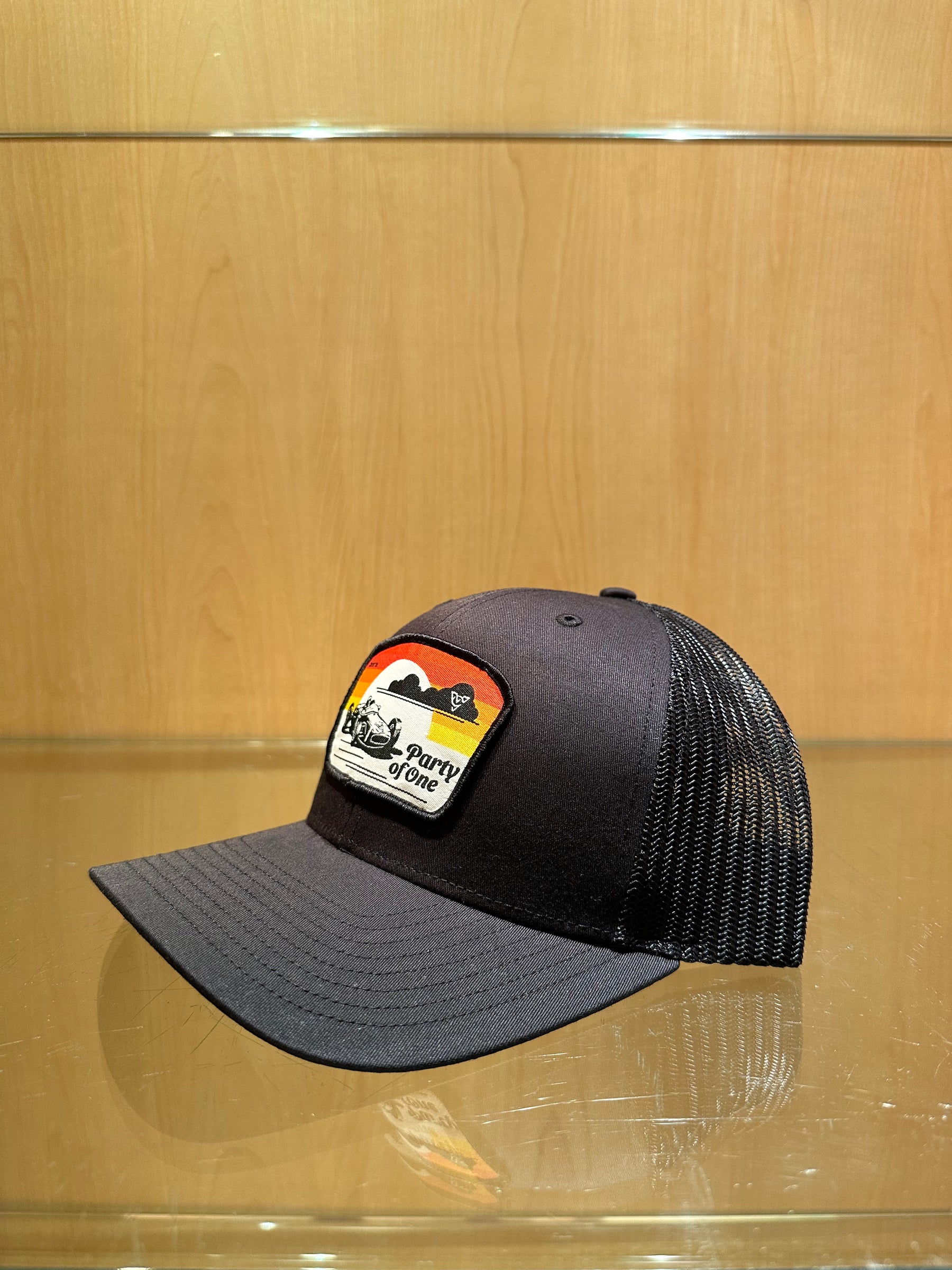 PARTY OF ONE (Black/Black Premium Trucker Hat)