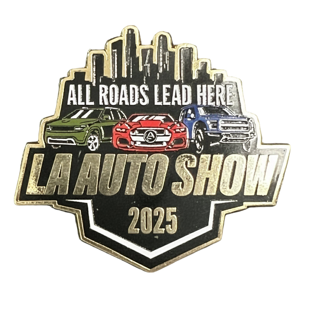 Pin with 'All Roads Lead Here LA Auto Show 2025' text and car illustrations on a textured background